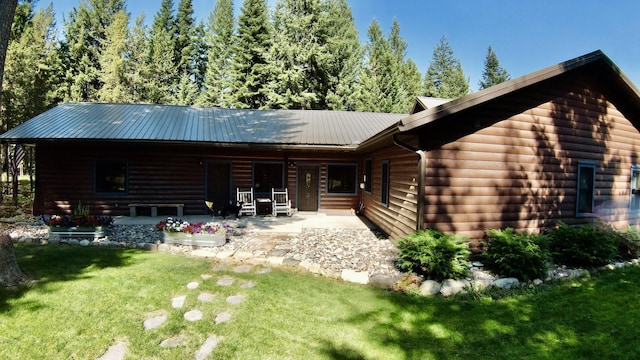 rear view of property featuring faux log siding, a lawn, and metal roof