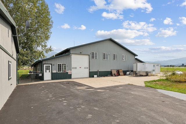 view of side of home featuring a mountain view, a garage, and an outbuilding