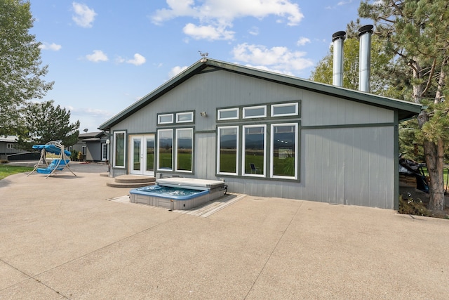 back of house featuring an outdoor hot tub and a patio