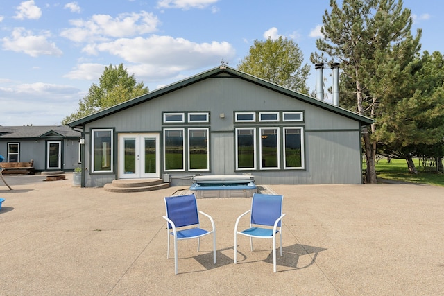 rear view of property with french doors, a hot tub, and a patio