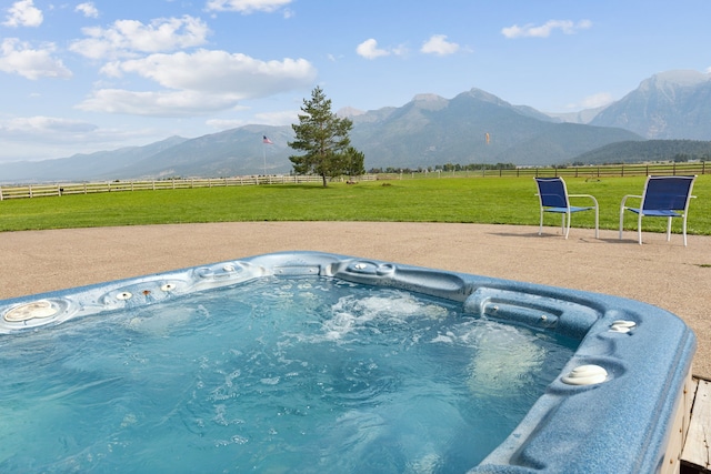 view of swimming pool with a mountain view, a hot tub, a rural view, and a lawn