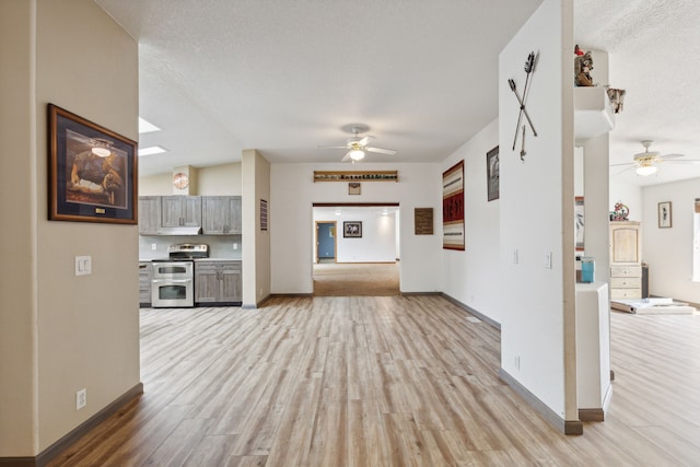 unfurnished living room with vaulted ceiling, a textured ceiling, light hardwood / wood-style flooring, and ceiling fan