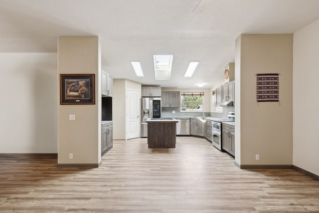 kitchen featuring a center island, stainless steel appliances, light hardwood / wood-style floors, gray cabinets, and a textured ceiling