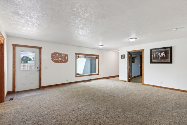 spare room featuring a textured ceiling and light colored carpet