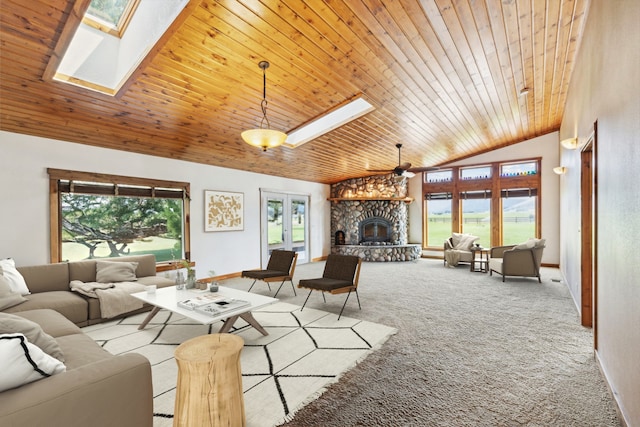 carpeted living room featuring a wealth of natural light, ceiling fan, a stone fireplace, and a skylight