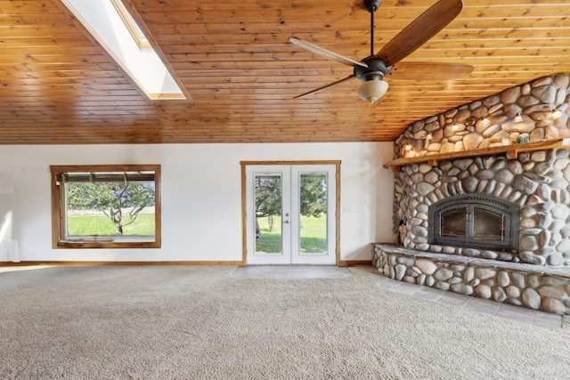 unfurnished living room featuring a skylight, ceiling fan, wooden ceiling, and a stone fireplace