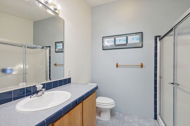 bathroom featuring tile patterned flooring, vanity, toilet, and a shower with shower door