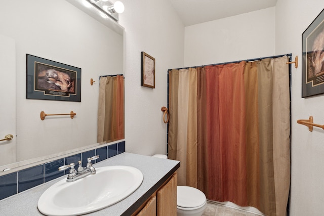 bathroom featuring vanity, toilet, and backsplash