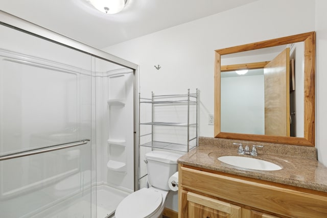 bathroom with a shower with door, vanity, and toilet