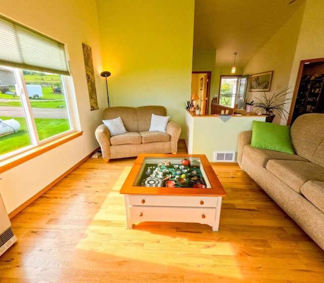 living room with high vaulted ceiling and light wood-type flooring