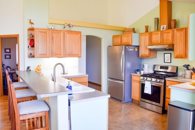 kitchen with a breakfast bar, kitchen peninsula, high vaulted ceiling, and appliances with stainless steel finishes