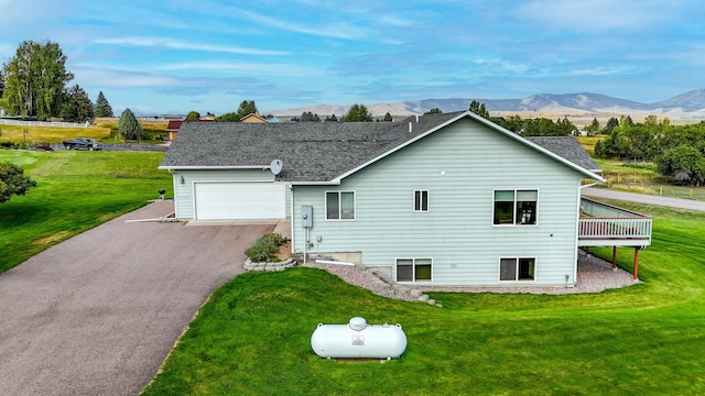 back of property featuring a mountain view, a garage, and a lawn