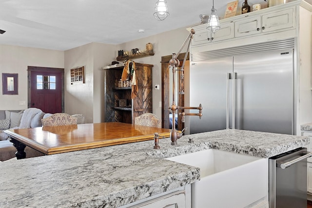 kitchen featuring decorative light fixtures, built in refrigerator, open floor plan, and white cabinetry