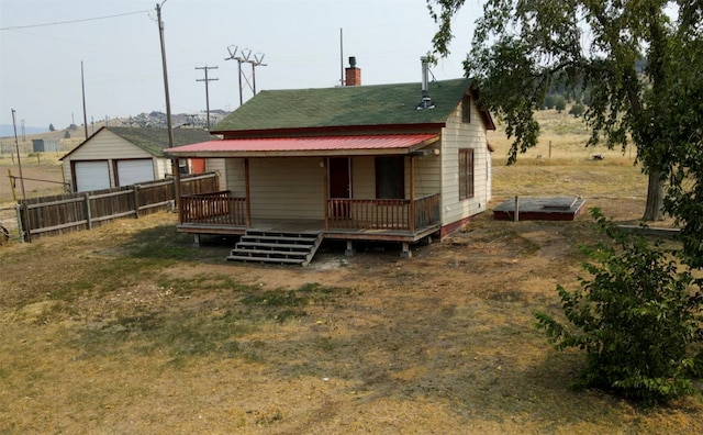 rear view of house featuring an outdoor structure, a garage, and a porch