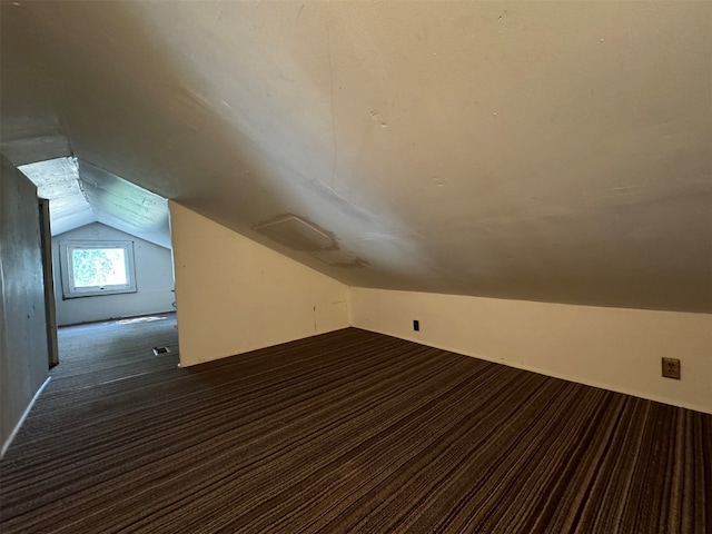 additional living space with lofted ceiling and dark carpet