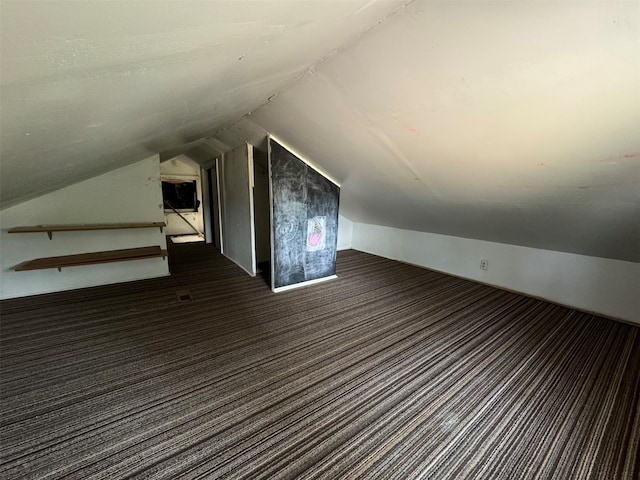 additional living space featuring vaulted ceiling and dark carpet