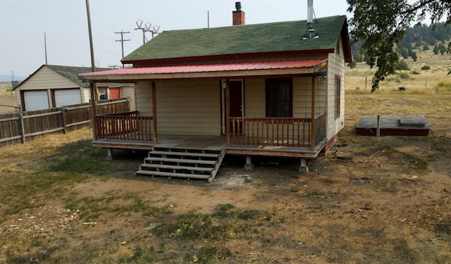 rear view of property featuring covered porch, an outbuilding, and a garage