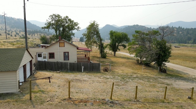 view of yard featuring a mountain view, an outdoor structure, a rural view, and a garage