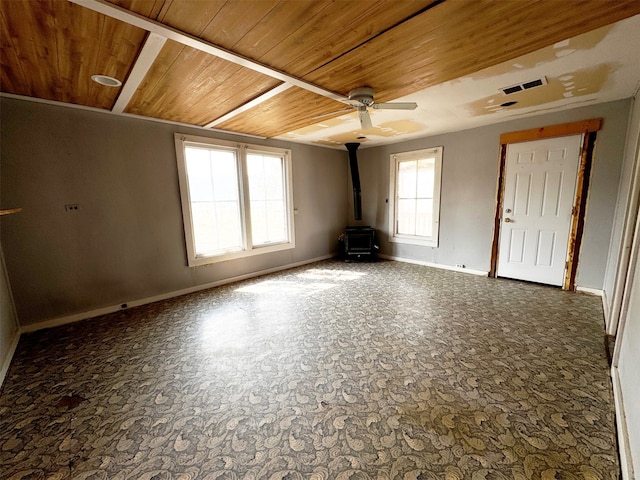 empty room with a wood stove, ceiling fan, and wood ceiling