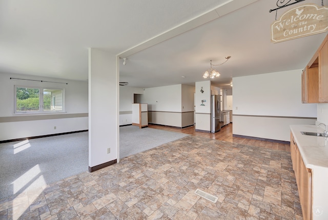 unfurnished living room featuring sink and a notable chandelier