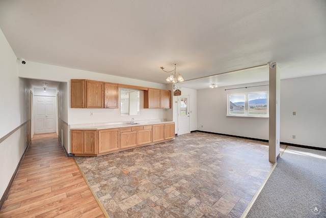 kitchen with a notable chandelier, sink, decorative light fixtures, and light hardwood / wood-style floors