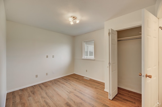 unfurnished bedroom featuring light hardwood / wood-style flooring and a closet