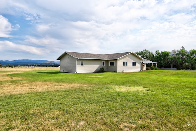 back of property featuring a mountain view, a lawn, and a rural view