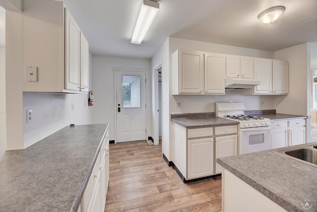 kitchen with light wood-type flooring, white gas stove, and white cabinetry