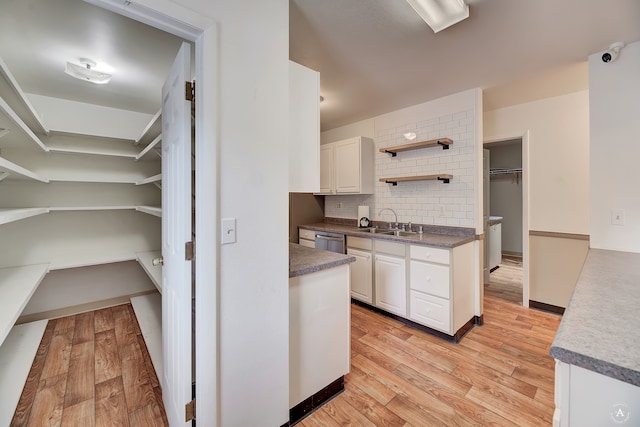 kitchen with white cabinets, dishwasher, light hardwood / wood-style flooring, sink, and tasteful backsplash