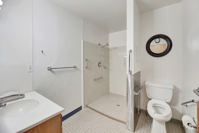 bathroom with vanity, toilet, tiled shower, and tile patterned flooring