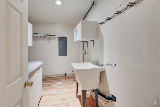 laundry area featuring electric panel and light wood-type flooring