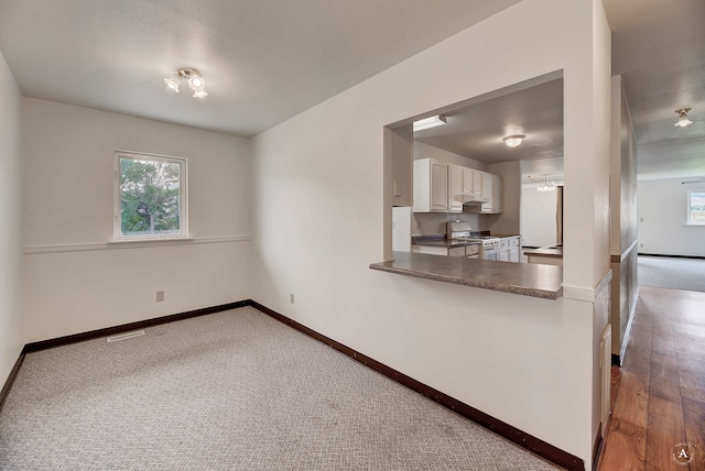 kitchen featuring white cabinetry, wood-type flooring, and gas range oven