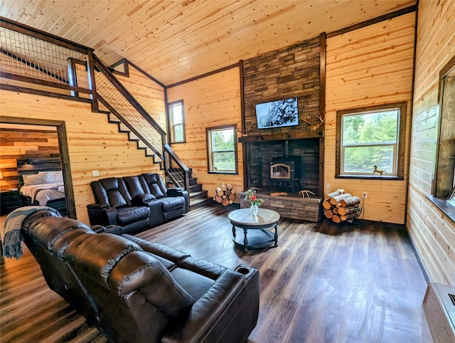 living room with wooden walls, wood-type flooring, high vaulted ceiling, and a fireplace