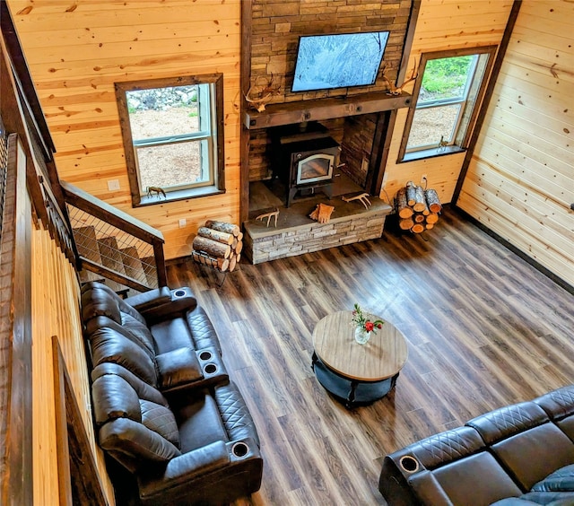 living room featuring a high ceiling, wood walls, wood-type flooring, and a wood stove