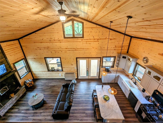 unfurnished living room with dark wood-type flooring, high vaulted ceiling, wooden walls, and ceiling fan