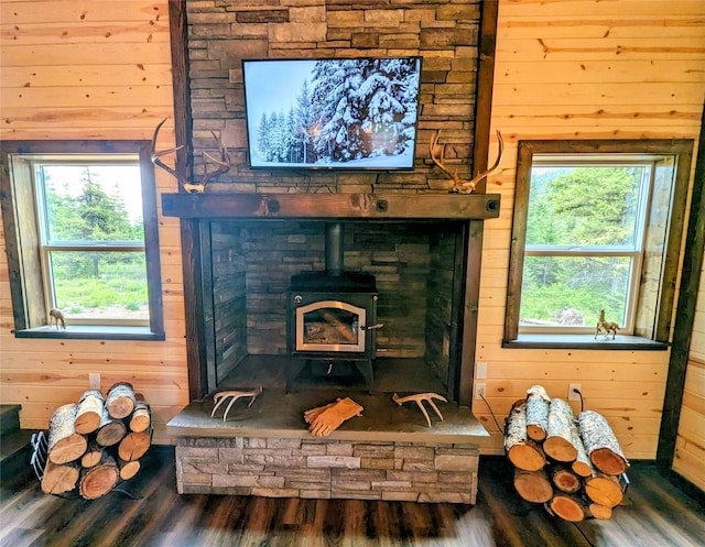 interior details featuring a wood stove, wood-type flooring, and wooden walls