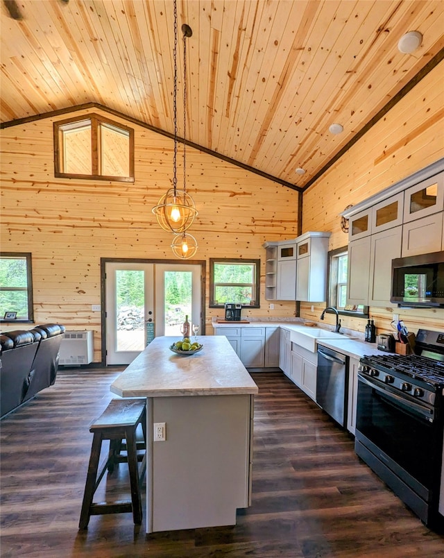 kitchen with decorative light fixtures, appliances with stainless steel finishes, dark hardwood / wood-style flooring, high vaulted ceiling, and a kitchen island