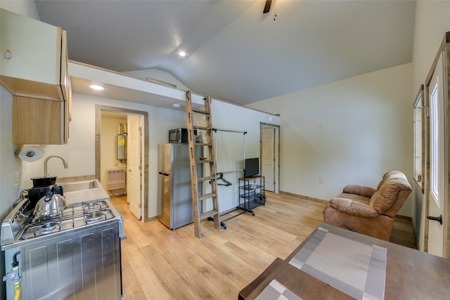 kitchen featuring light wood-type flooring, water heater, sink, appliances with stainless steel finishes, and lofted ceiling