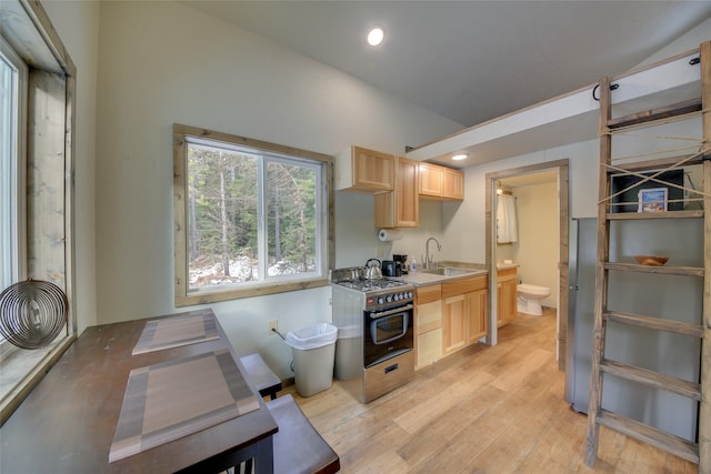 kitchen featuring light hardwood / wood-style flooring, light brown cabinetry, stainless steel gas range oven, and sink