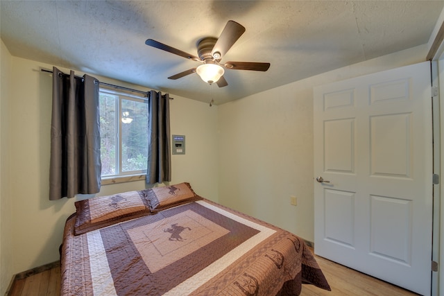 bedroom with a textured ceiling, ceiling fan, and light hardwood / wood-style floors