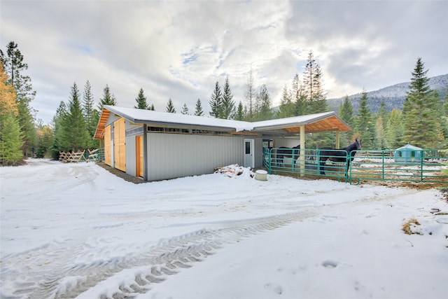 snow covered property featuring an outbuilding and a mountain view