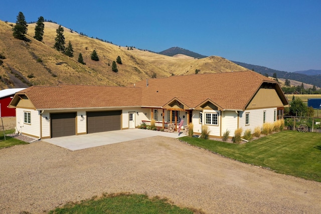 single story home featuring a porch, a garage, a mountain view, and a front lawn