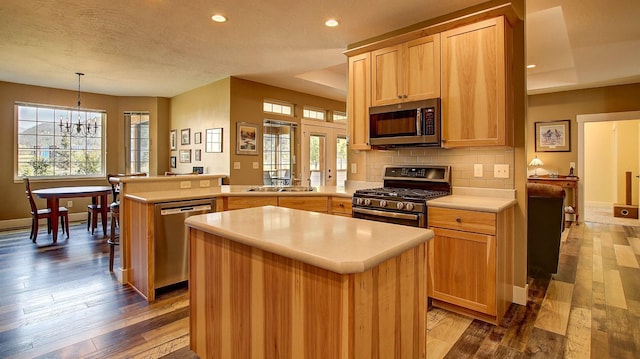 kitchen featuring pendant lighting, appliances with stainless steel finishes, kitchen peninsula, and a kitchen island