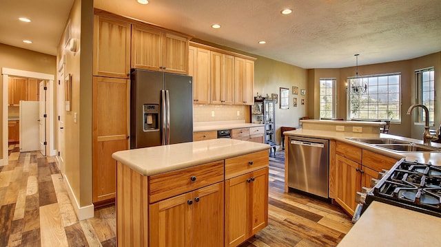 kitchen with pendant lighting, sink, backsplash, stainless steel appliances, and a kitchen island