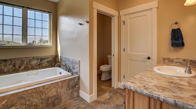 bathroom featuring vanity, toilet, and tiled tub