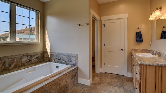 bathroom with vanity, tiled bath, and toilet