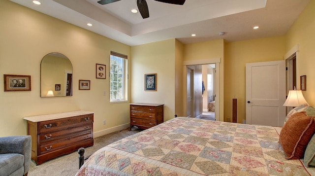 bedroom with light carpet, ceiling fan, and a tray ceiling