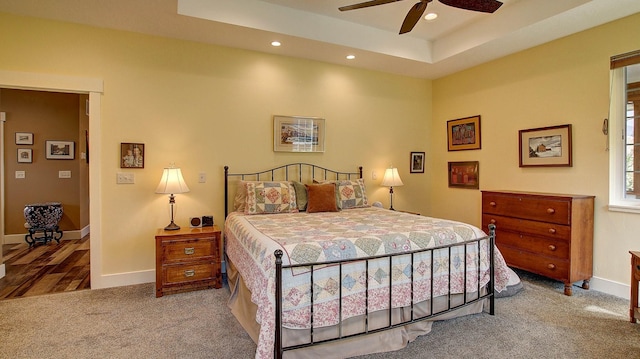 bedroom with ceiling fan, a raised ceiling, and carpet floors