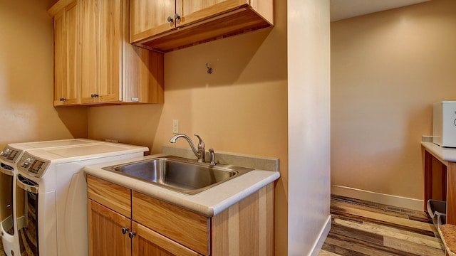 clothes washing area featuring sink, light hardwood / wood-style flooring, cabinets, and independent washer and dryer