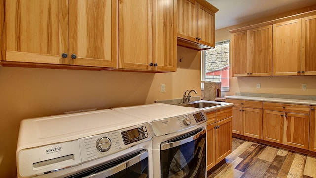 laundry area featuring dark wood-type flooring, cabinets, sink, and washing machine and clothes dryer